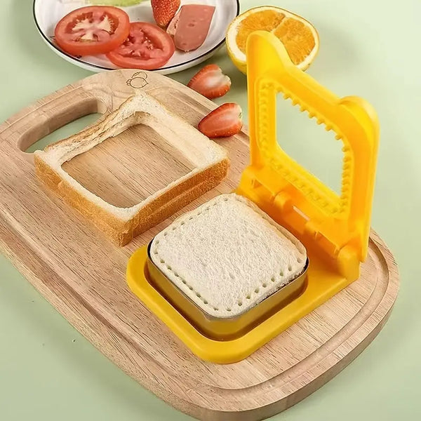 Yellow plastic sandwich cutter and sealer on wooden board with square sealed bread and fruit