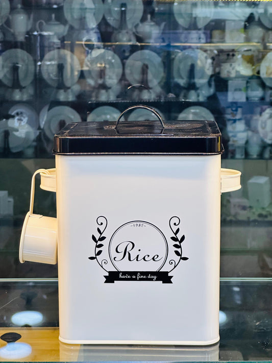 White rectangular metal 5 liter rice storage bucket with black lid and scoop attached and decorative Rice label