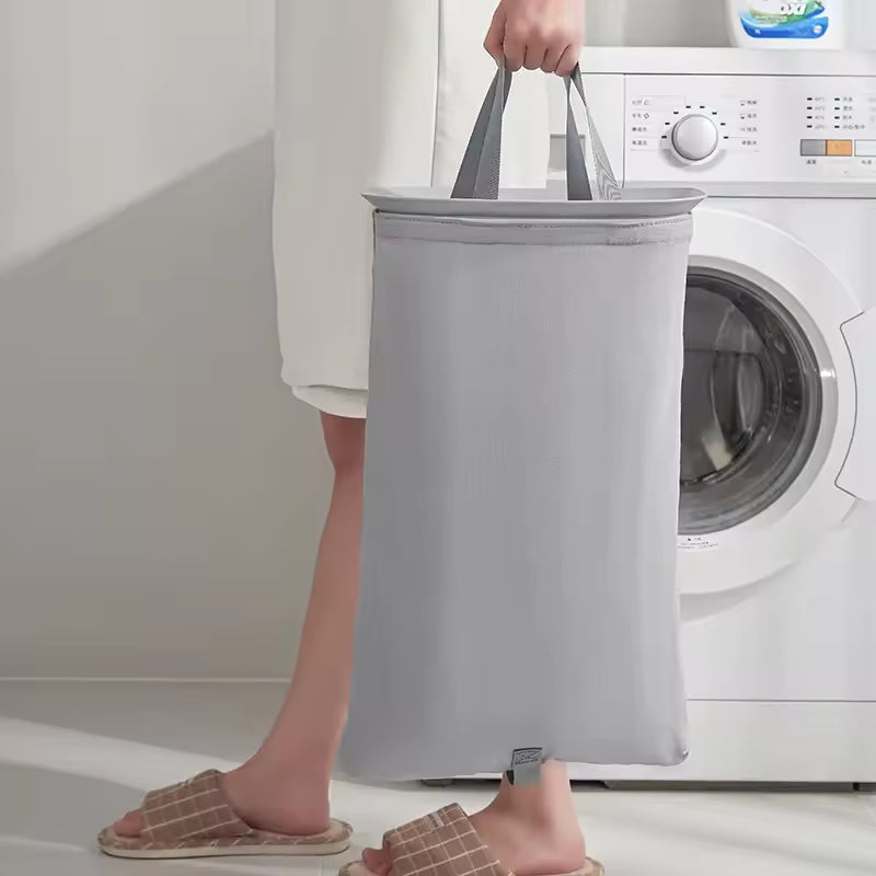 Person holding a gray Japanese style clothes hamper with handles in front of a washing machine