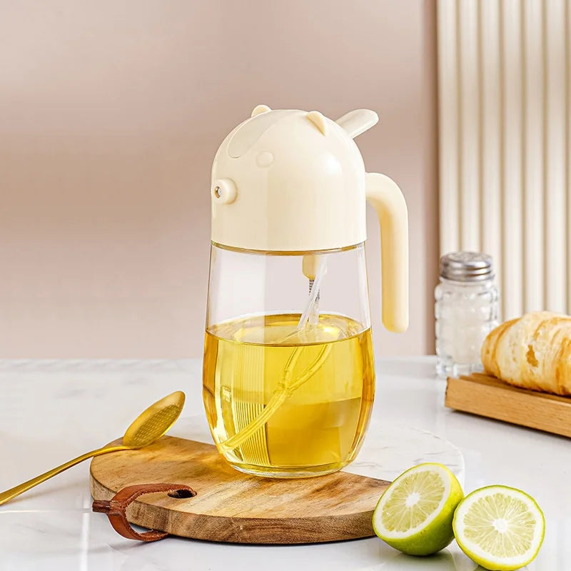 2 in 1 olive oil dispenser with a clear body and beige top, placed on a wooden board with lemon halves and a spoon nearby