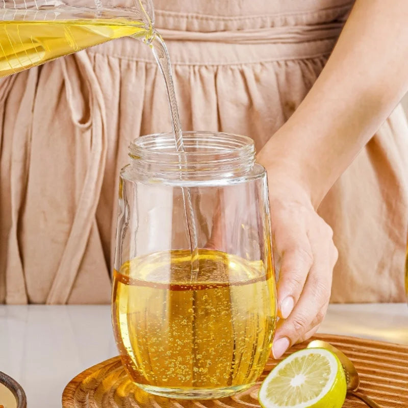 2 in 1 olive oil dispenser pouring oil into a glass jar with lemon slice on wooden tray