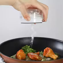 Kitchen magnetic spice jar from Clarify.pk dispensing spice over cooked chicken in a black pan