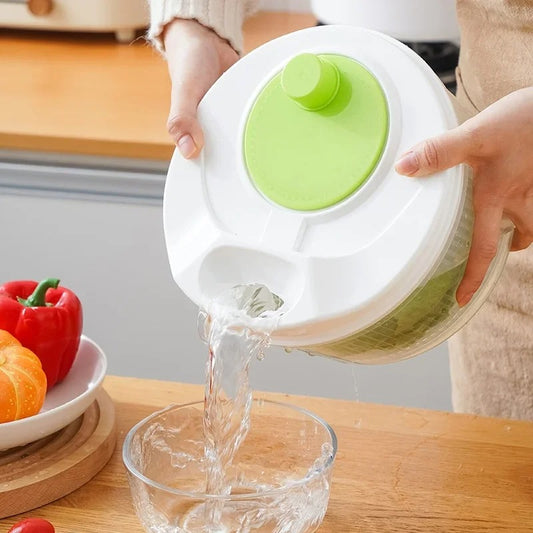 Person pouring water from clear salad spinner with green lid into bowl multifunctional lettuce drain basket for rinsing greens