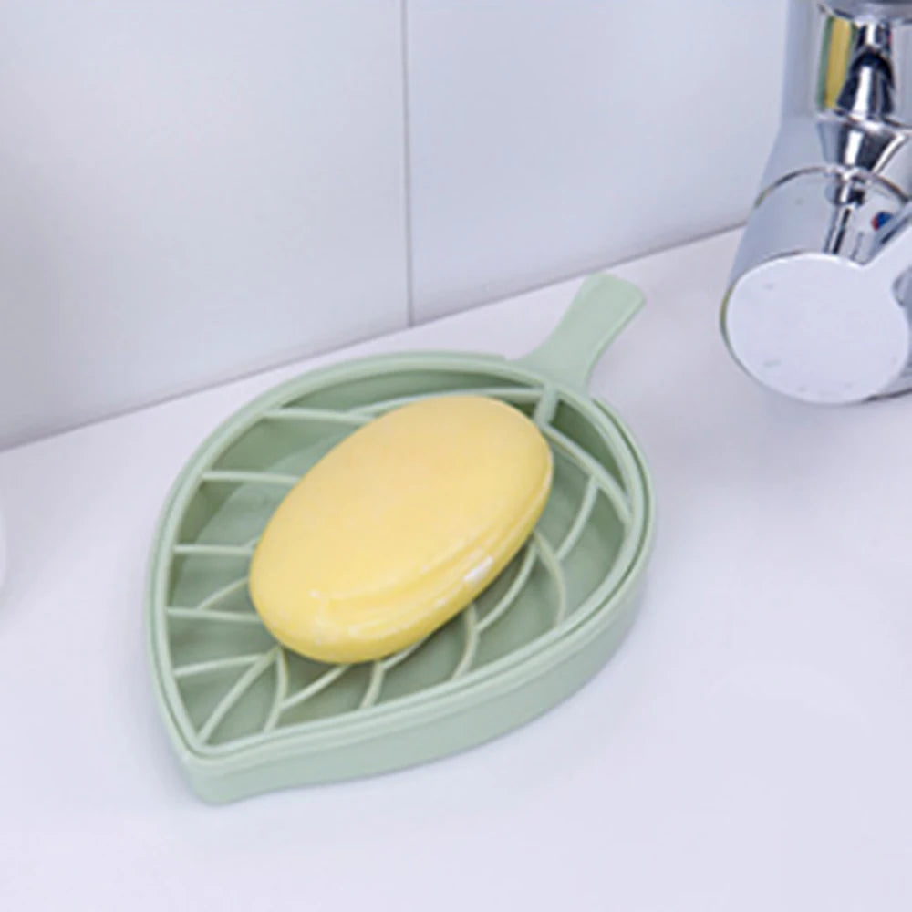 Clarify.pk leaf shape soap dish in green holding a yellow bar of soap on a white bathroom sink