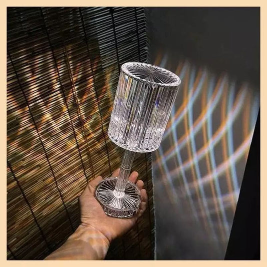 Hand holding a clear led crystal projection lamp casting colorful light patterns on walls