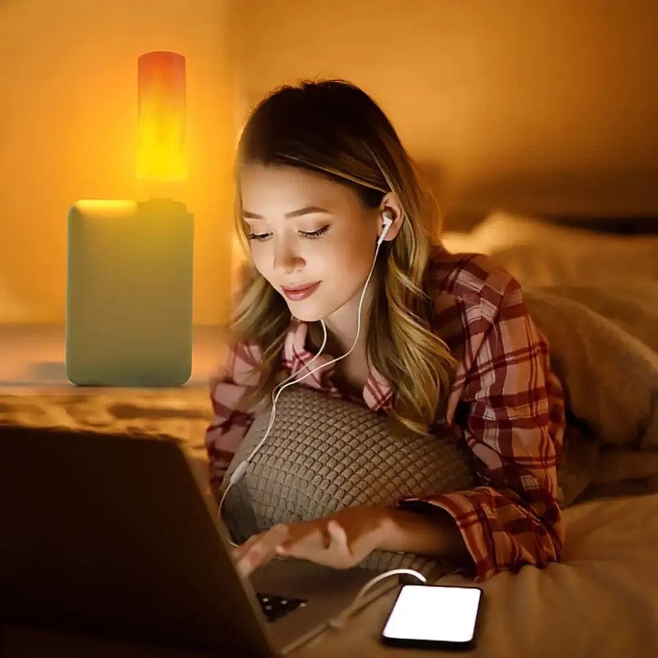 LED flame effect night light casting warm glow near woman using laptop in cozy bedroom