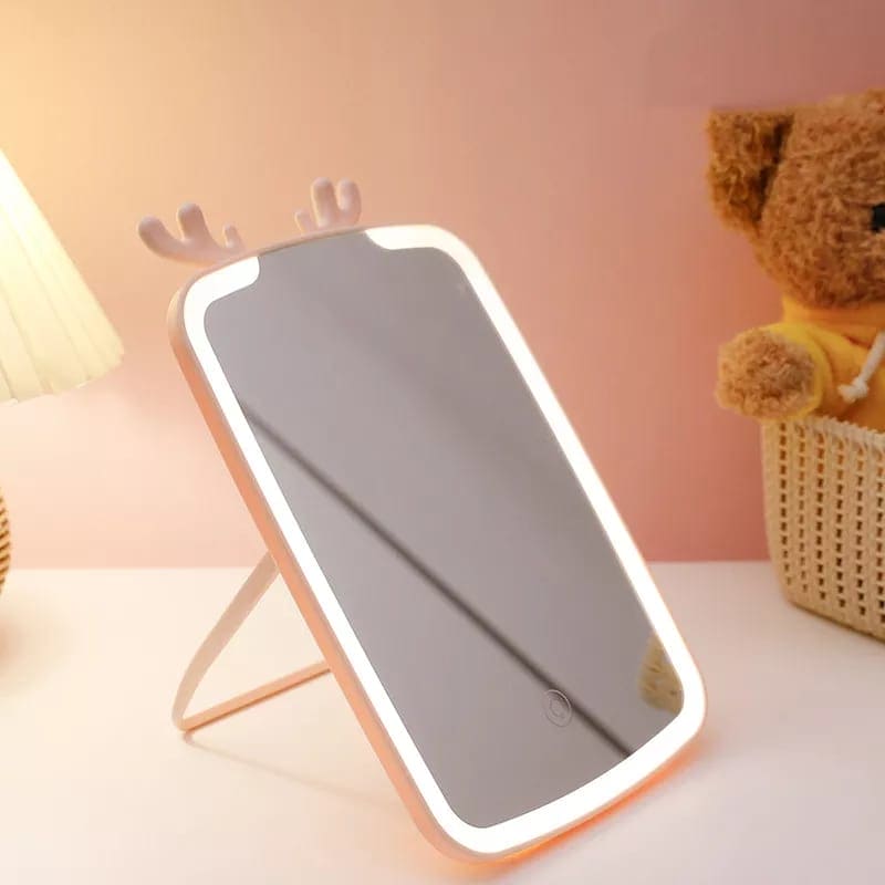 LED makeup mirror with lights and deer antler design on a white table near teddy bear
