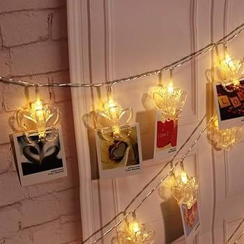 Warm white LED photo clip string lights hanging on wall with decorative clips holding photos