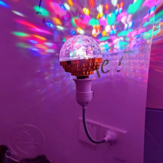 LED rotating disco ball light plugged into wall socket projecting colorful patterns on purple wall