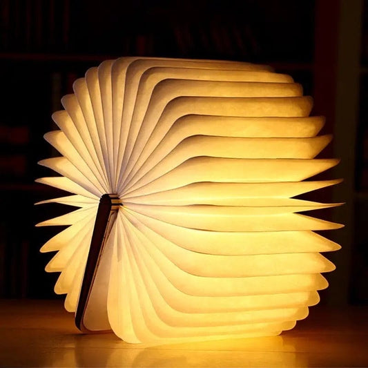 Illuminated LED wooden book lamp glowing warmly with open pages design on wooden surface