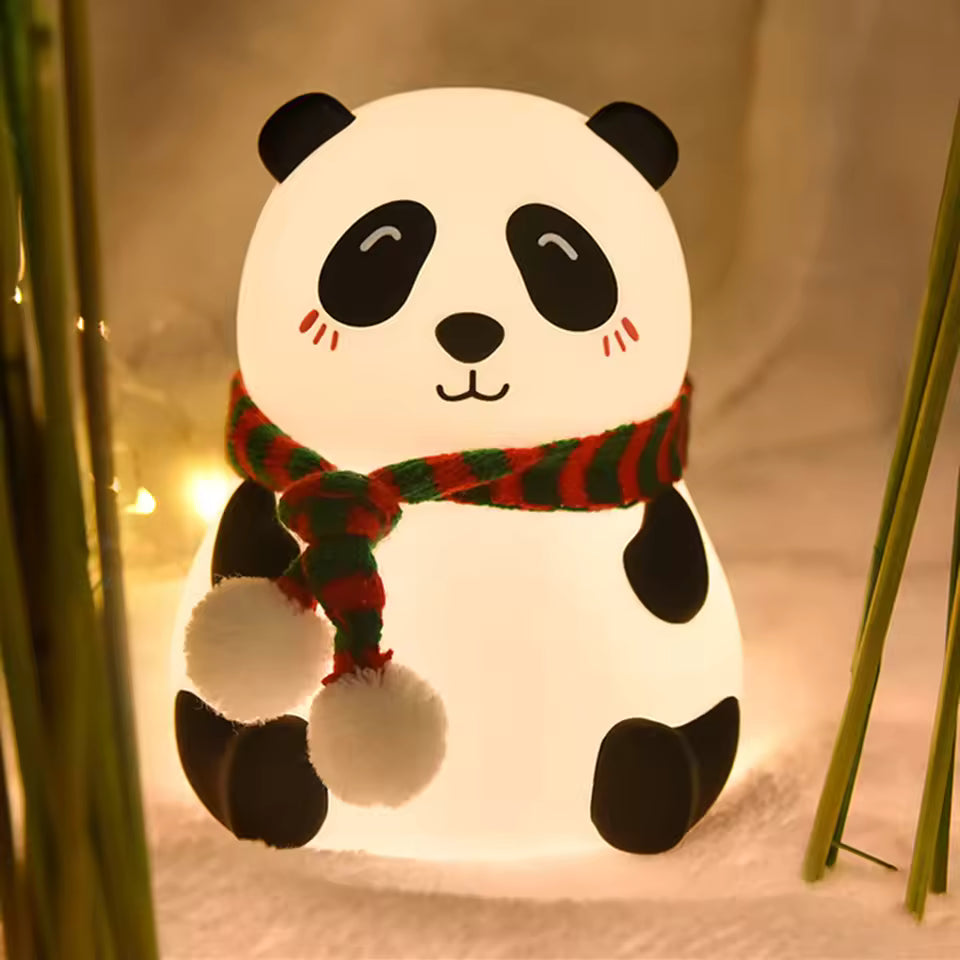 Cute silicone panda lamp night light with red and green scarf glowing softly in warm setting