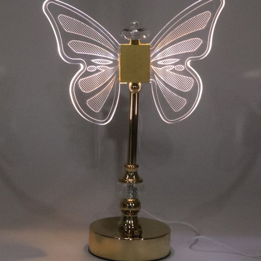 Illuminated butterfly table lamp with golden base and clear acrylic wings glowing softly