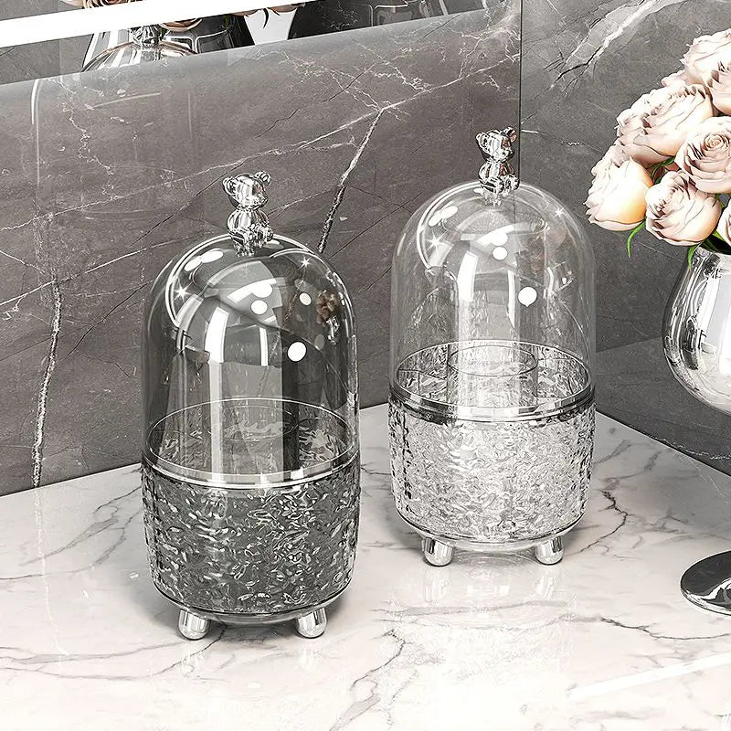 Luxury makeup brush organizer with glass dome and ornate silver base displayed on marble countertop
