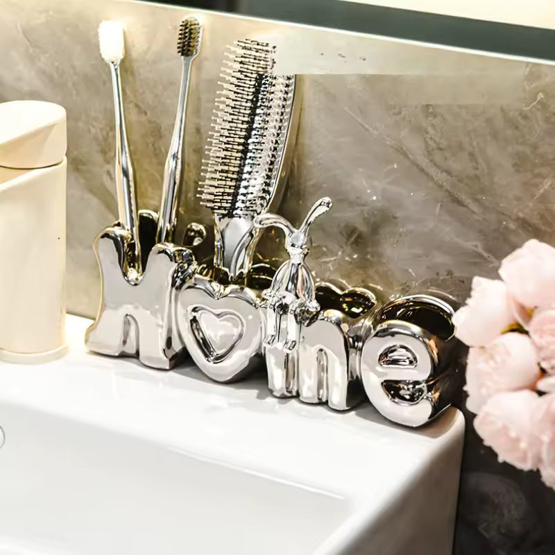 Luxury toothbrush holder for bathroom in shiny silver letters holding toothbrushes and a comb