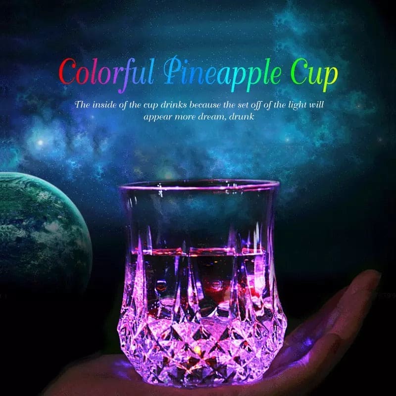 Magic light up acrylic mug glowing with colorful lights held in hand against dark space background
