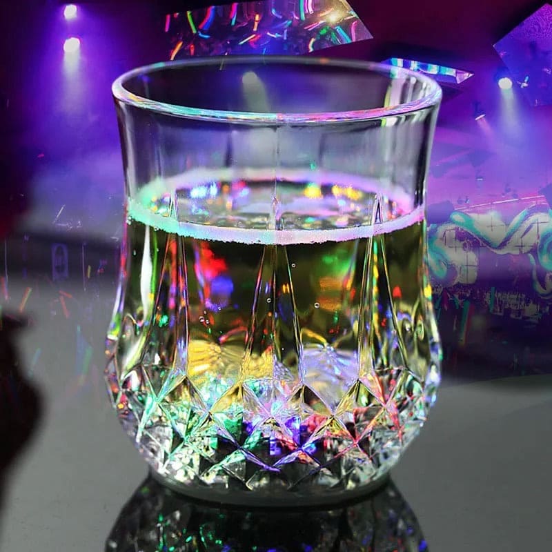 Clear magic light up acrylic mug glowing with colorful LED lights on a dark reflective surface