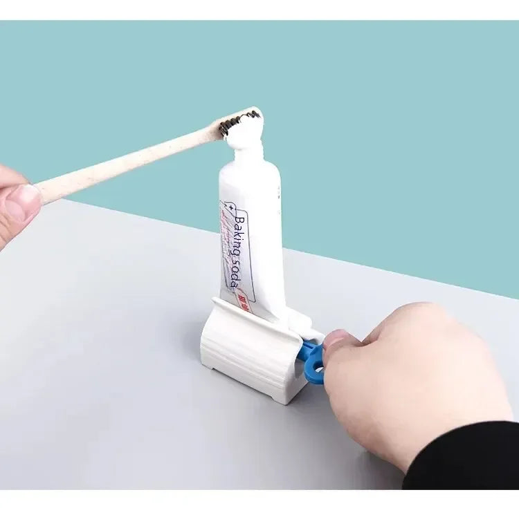 Manual toothpaste squeezer in use with a white tube dispensing toothpaste onto a toothbrush