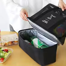 Black insulated mesh beach bag with pockets holding drinks and snacks on a wooden table