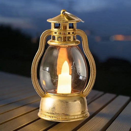 Gold vintage style mini lantern lamp for home decor with glowing candle inside on wooden surface