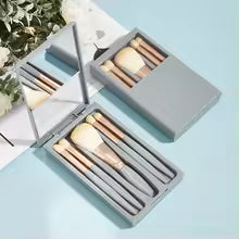 Mini makeup brush set with case featuring various brush types in a compact gray container with mirror