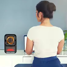 Compact mini portable room heater on desk next to woman working on computer in home office