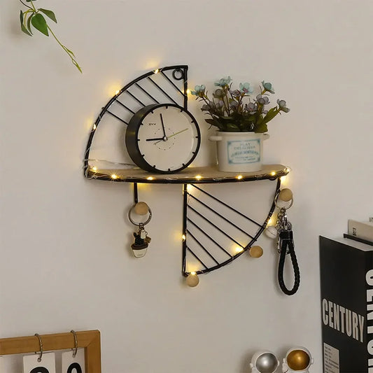 Minimalist home decor shelf with black metal geometric design holding a clock and plant with hanging keys and fairy lights