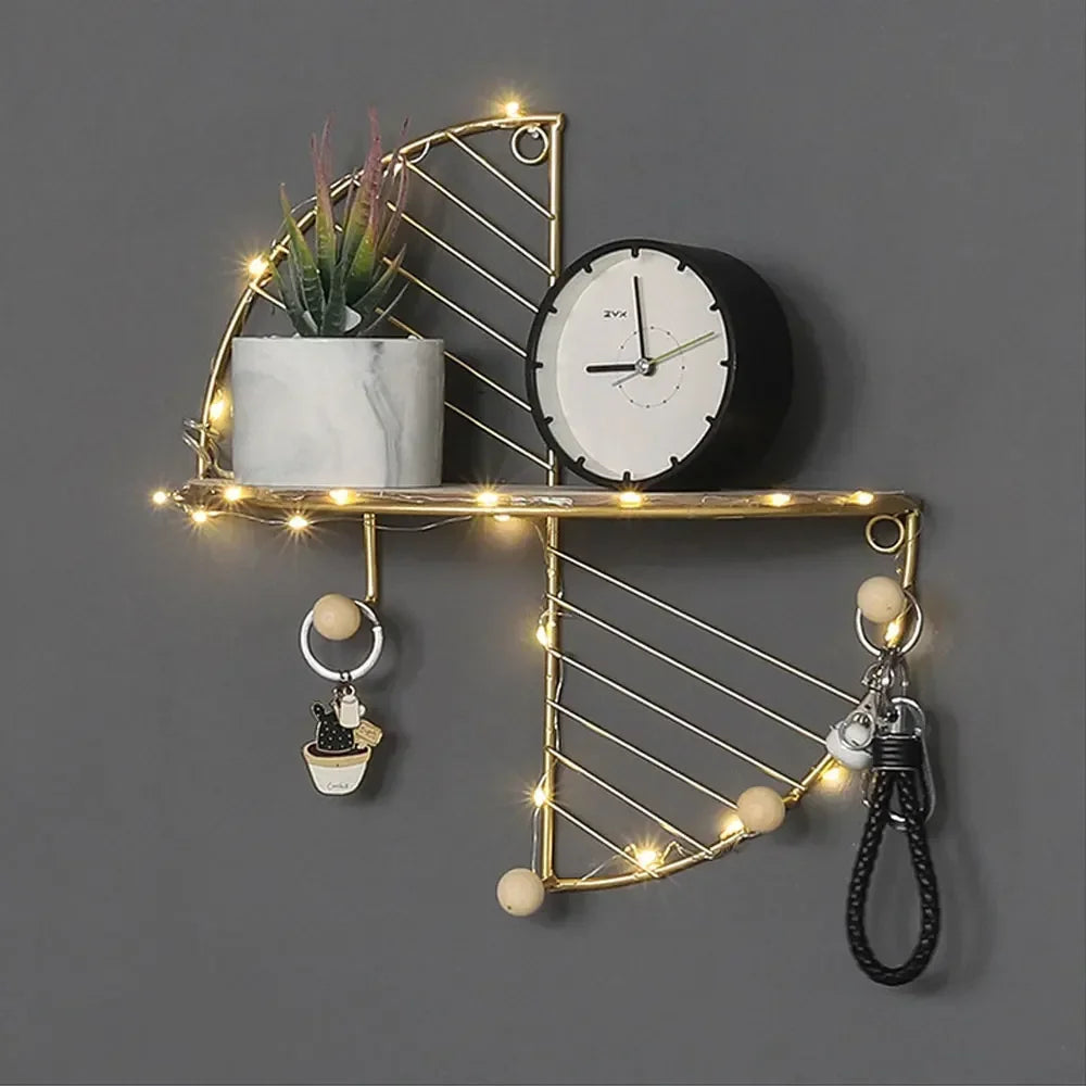Minimalist home decor shelf with gold metal frame, clock, potted plant, and hanging keychains with string lights