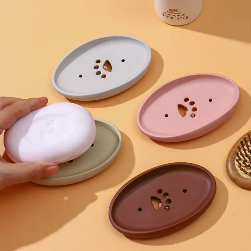 Set of multifunctional silicone soap box in various colors holding white soap and designed with drainage holes