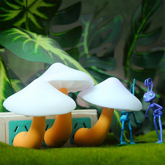 Mushroom LED night light with white caps plugged into an outlet surrounded by green leaves and toy figures