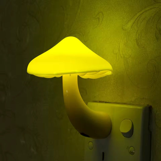 Yellow glowing mushroom night light LED plugged into wall outlet in dark room