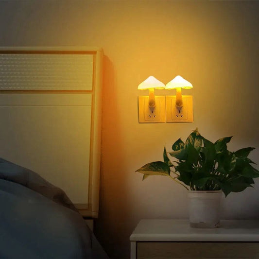 Two mushroom night light plug in glowing warmly on a bedroom wall near a bed and a plant