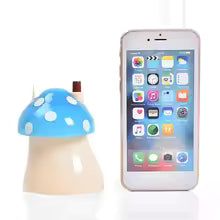 Mushroom toothpick holder with blue cap and white spots next to a smartphone for size comparison