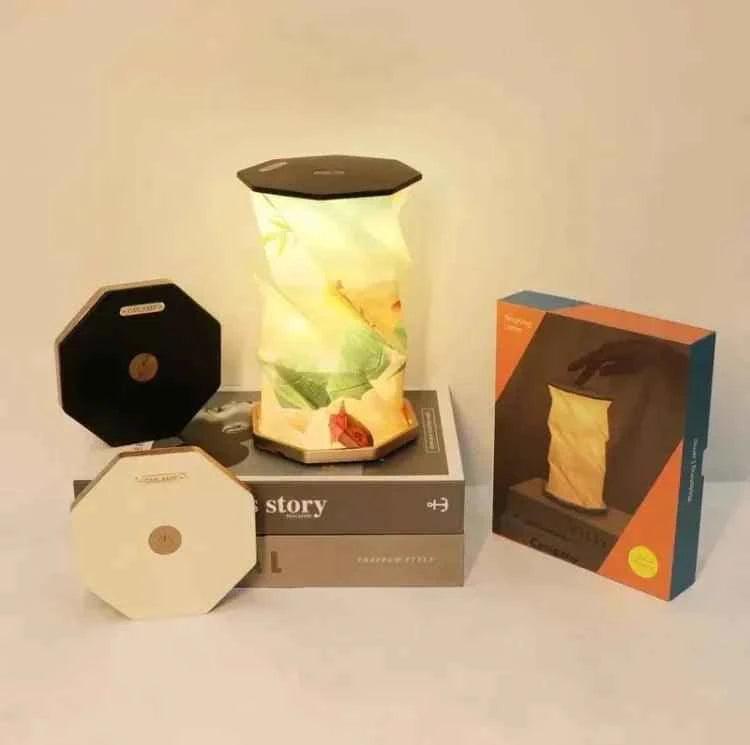 Clarify.pk LED table lamp with floral design placed on books alongside folded black and white lamp bases and packaging box