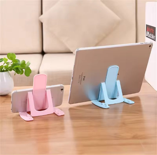 Pack of 4 cell phone stands in pink and blue holding a smartphone and tablet on wooden table