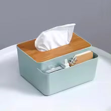 Plastic tissue box with wooden lid in light green with side storage compartment on white table