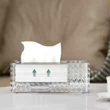 Clear plastic tissue organizer box with decorative pattern holding white tissues on a table