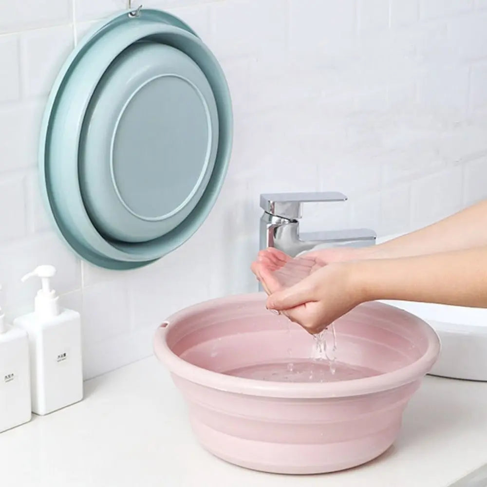 Clarify.pk portable folding laundry tub in pink being used to catch water from a faucet with folded tubs hanging on wall