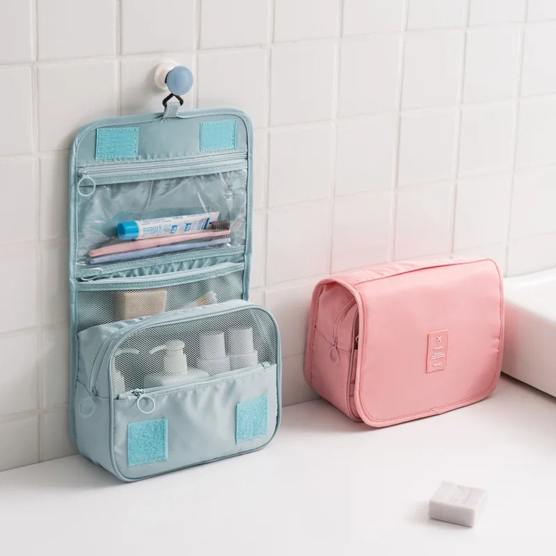 Clarify.pk portable hanging toiletry bag in blue with multiple compartments and a pink cosmetic case on a bathroom counter