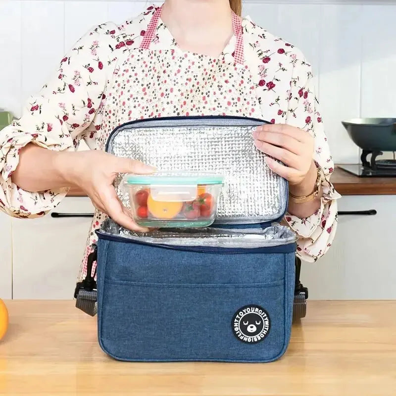 Clarify.pk portable insulated lunch bag in Oxford cloth with silver interior and blue exterior held open by a person