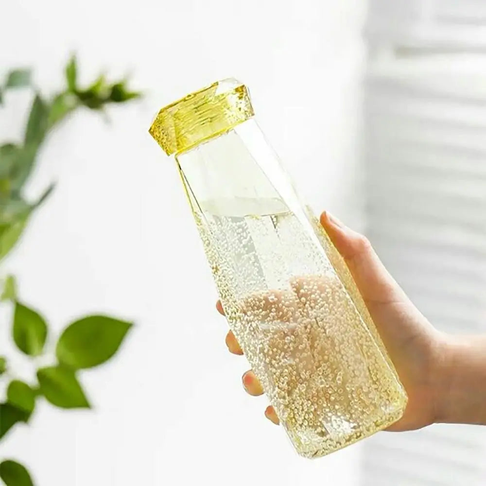 Hand holding clear yellow portable sport drink bottle filled with water and bubbles