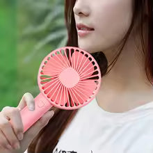 Clarify.pk rechargeable mini portable fan in pink handheld by woman outdoors for personal cooling
