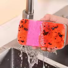 Hand holding reusable dishcloths for kitchen in red and pink colors under running faucet water