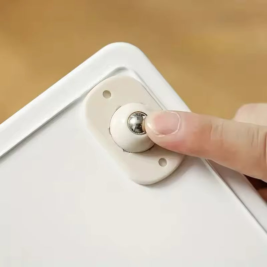 Person pressing small white self adhesive furniture wheels ball caster onto furniture corner