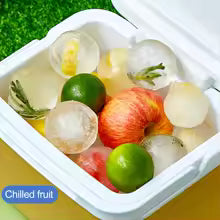 Silicone sphere ice mold with large round ice balls and fresh fruit in a cooler box