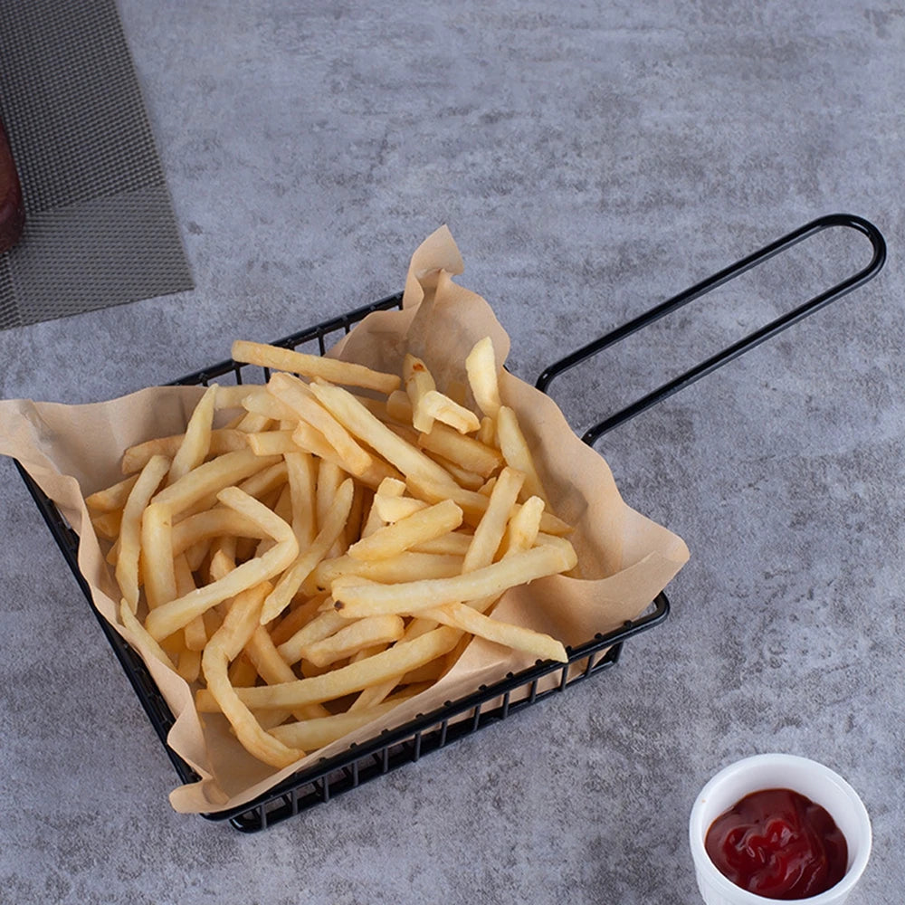 Black wire snack bucket with crispy French fries and a side of ketchup on gray surface