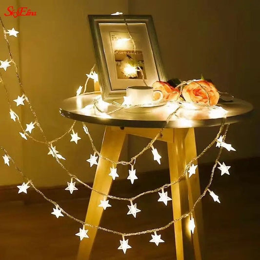 LED star curtain lights for decoration draped over a wooden table with flowers and a photo frame