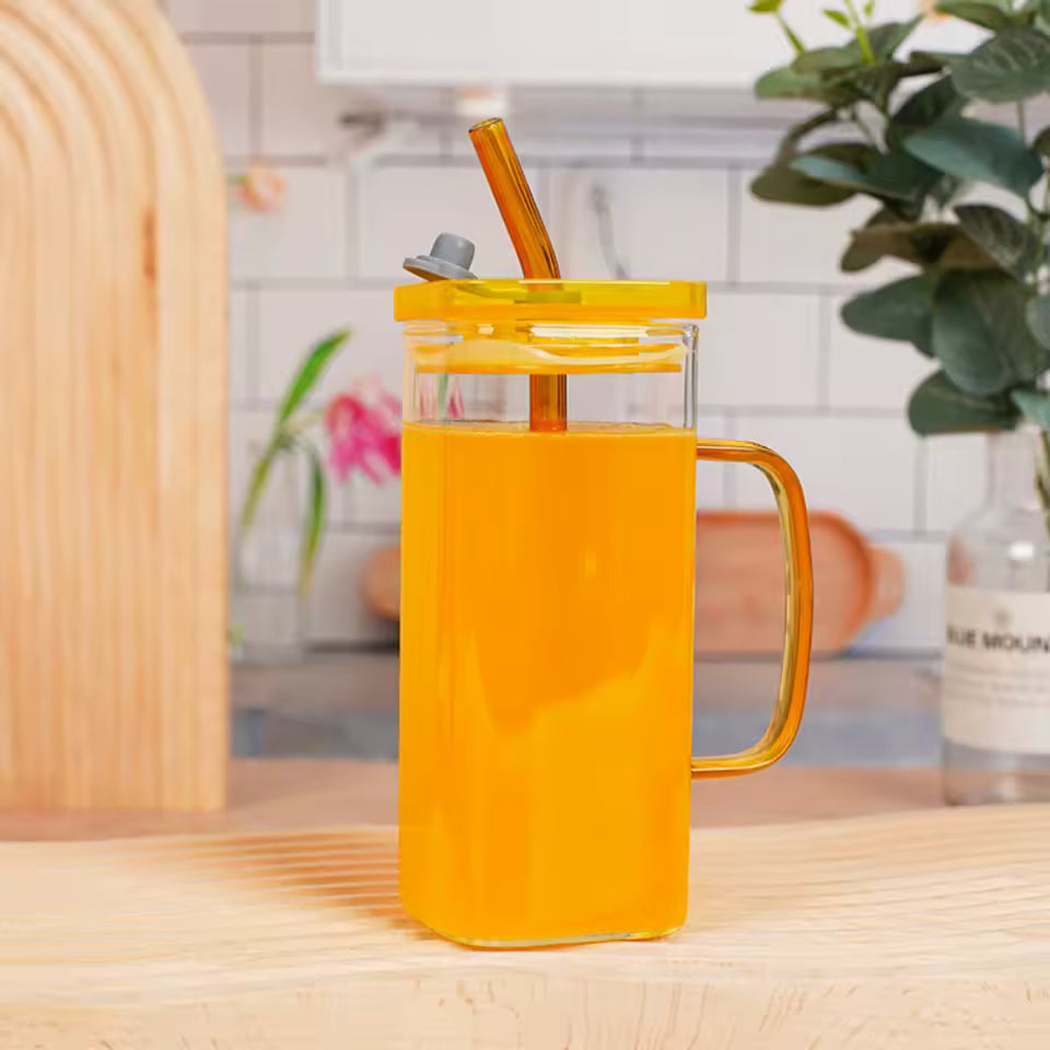 Clarify.pk transparent glass bottle with yellow lid and handle filled with orange juice on wooden table