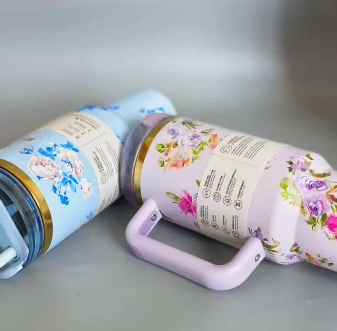 Two Clarify.pk stainless steel flower tumblers with floral patterns and sturdy handles