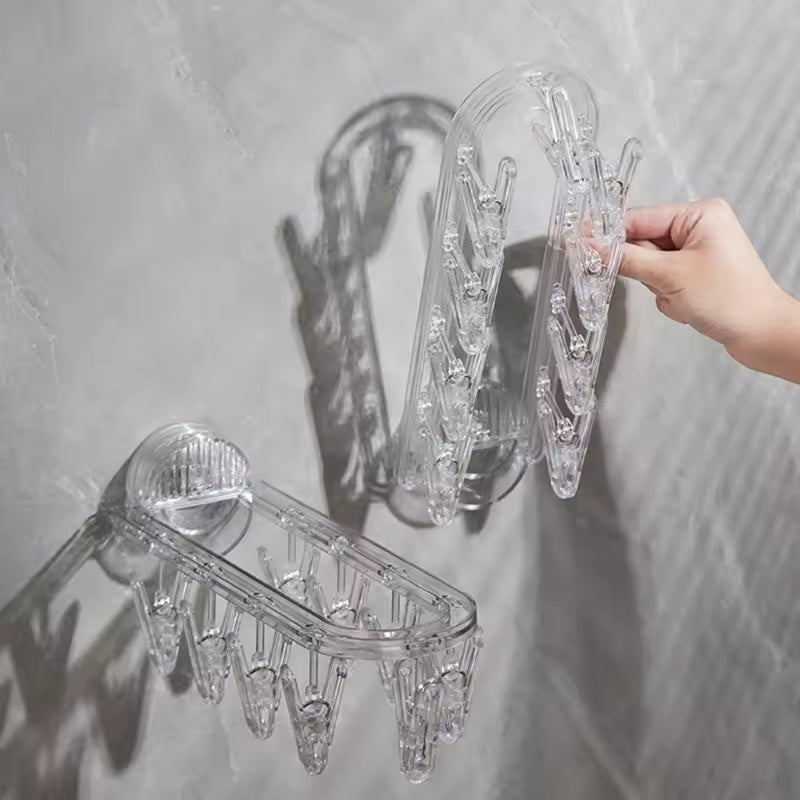 Clear plastic suction clothes hanger rack with multiple clips mounted on a tiled wall