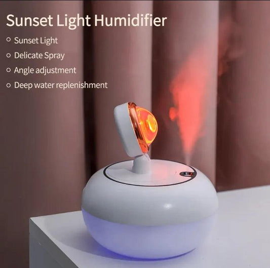 White sunset light humidifier with adjustable angle and glowing orange light misting on table